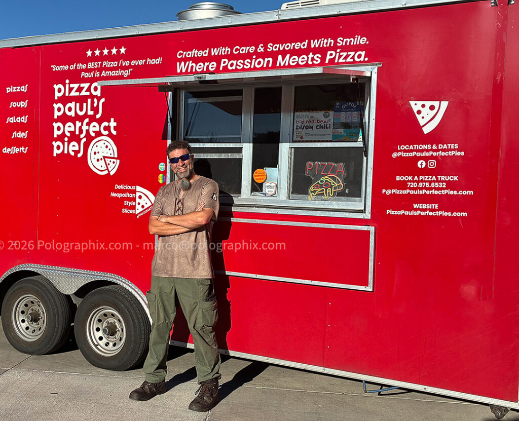 A food truck and it's owner standing in front of it.